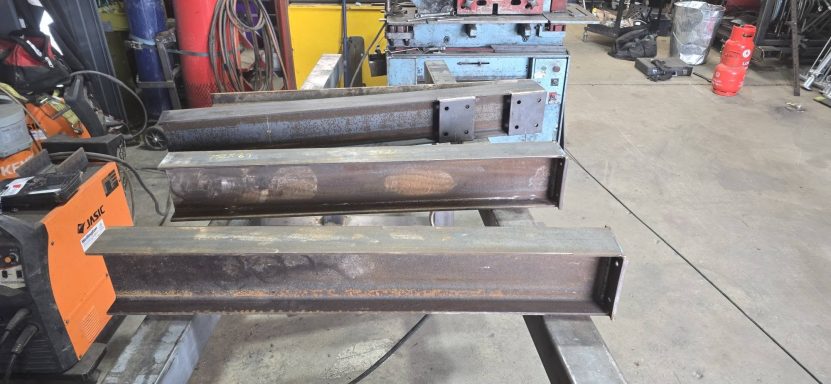 Fabricated steel beams with welded end plates in the workshop, Rackheath, Norwich Three steel I-beams with welded end plates on stands in the fabrication workshop