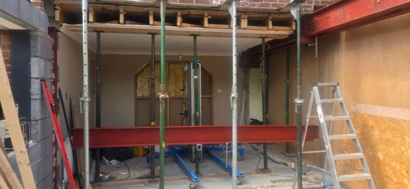 Red steel beam on props in a house extension opening, Norfolk
