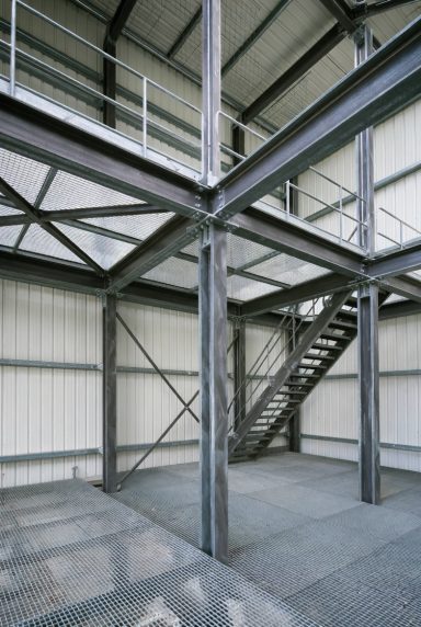 Industrial interior featuring steel beams, stairs, and a spacious, minimalist design.